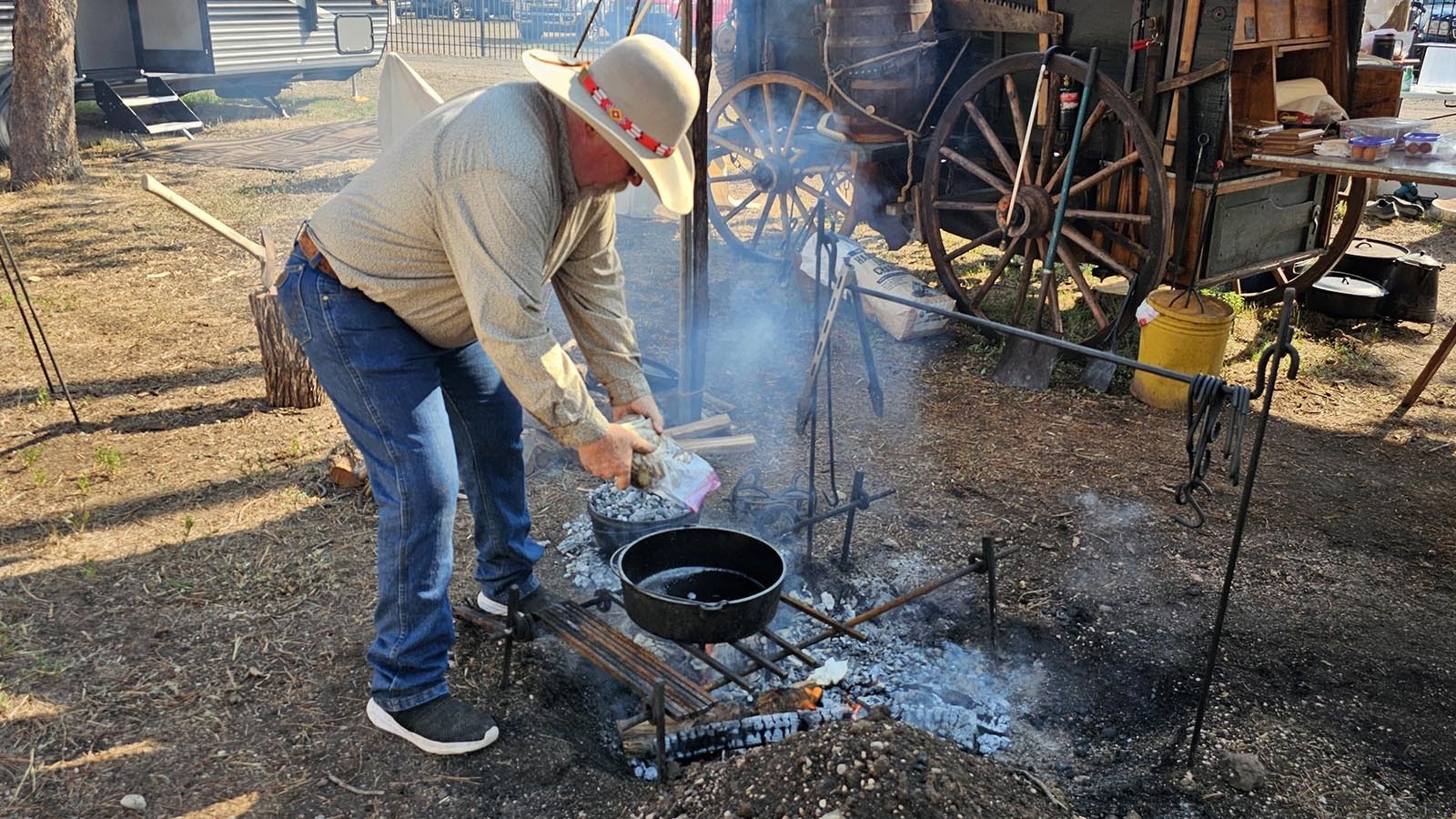 Rich Herman adds a brick of frozen potatoes to a Dutch Oven to reheat them for breakfast the last day of Cheyenne Frontier Days.