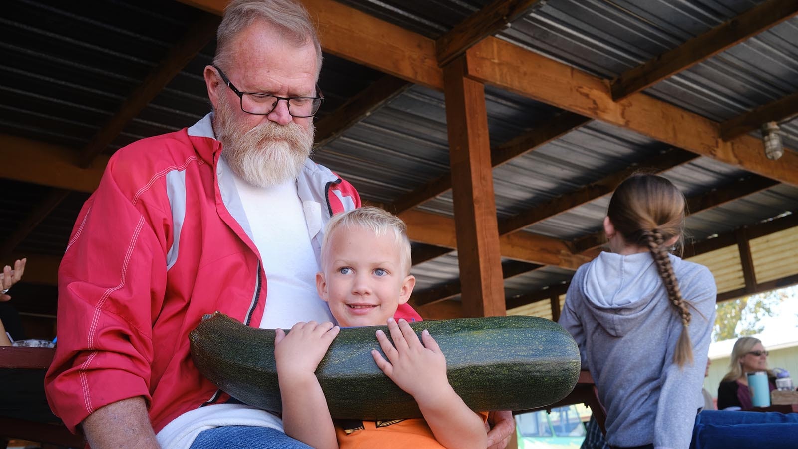 Four-year-old Stanley Richard shows his grandfather, Scott Richard, the giant zucchini he grew. The pair sat in the front row at the 2024 Wyoming State Pumpkin Weigh-Off on Oct. 5, 2024.