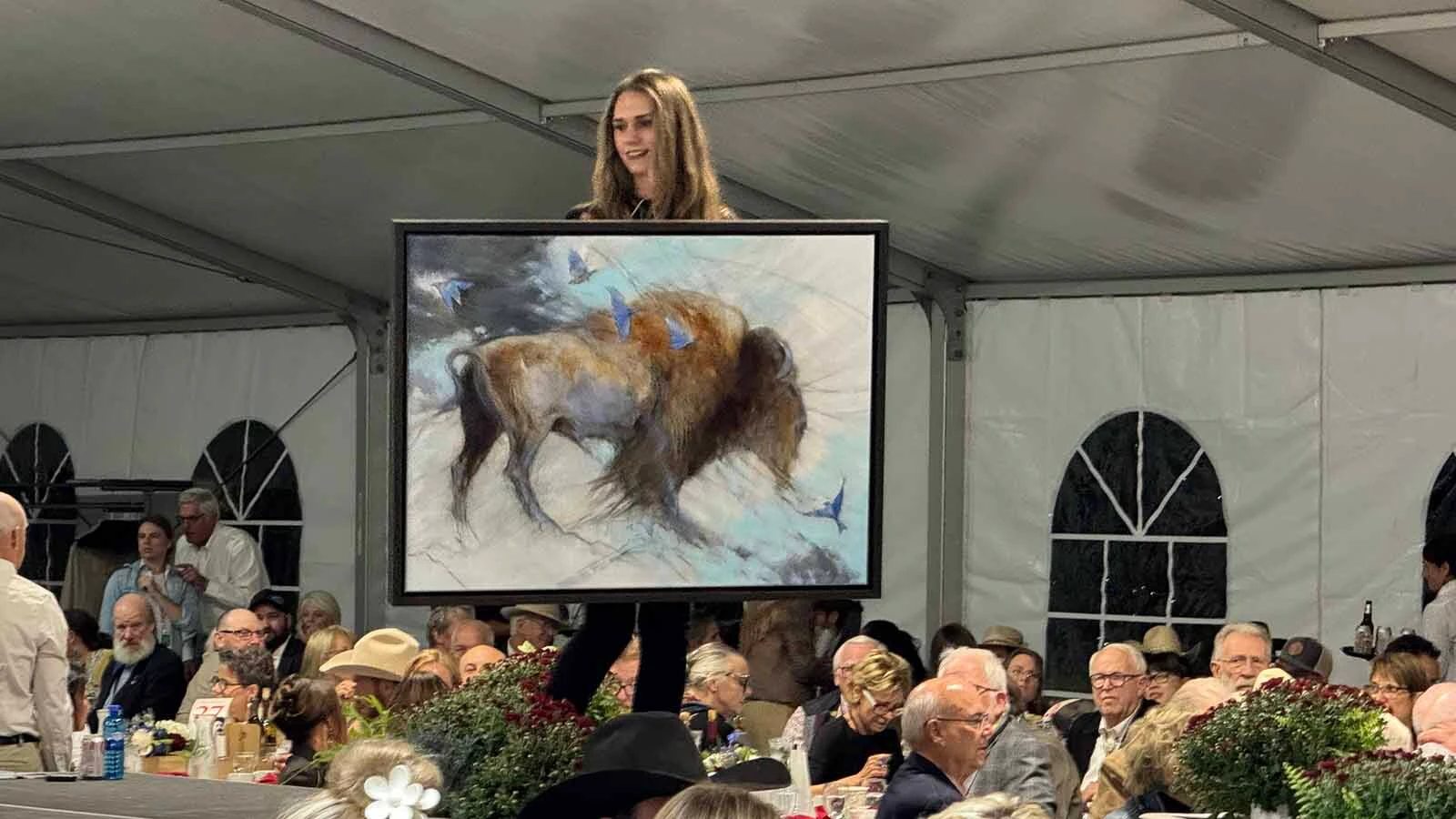 "A Blue West Wind," an oil painting by Amy Lay, on the partially lit runway of the 45th Buffalo Bill Art Show and Sale on Friday. Despite a city-wide power outage, the auction commenced and the painting sold for $8,000.