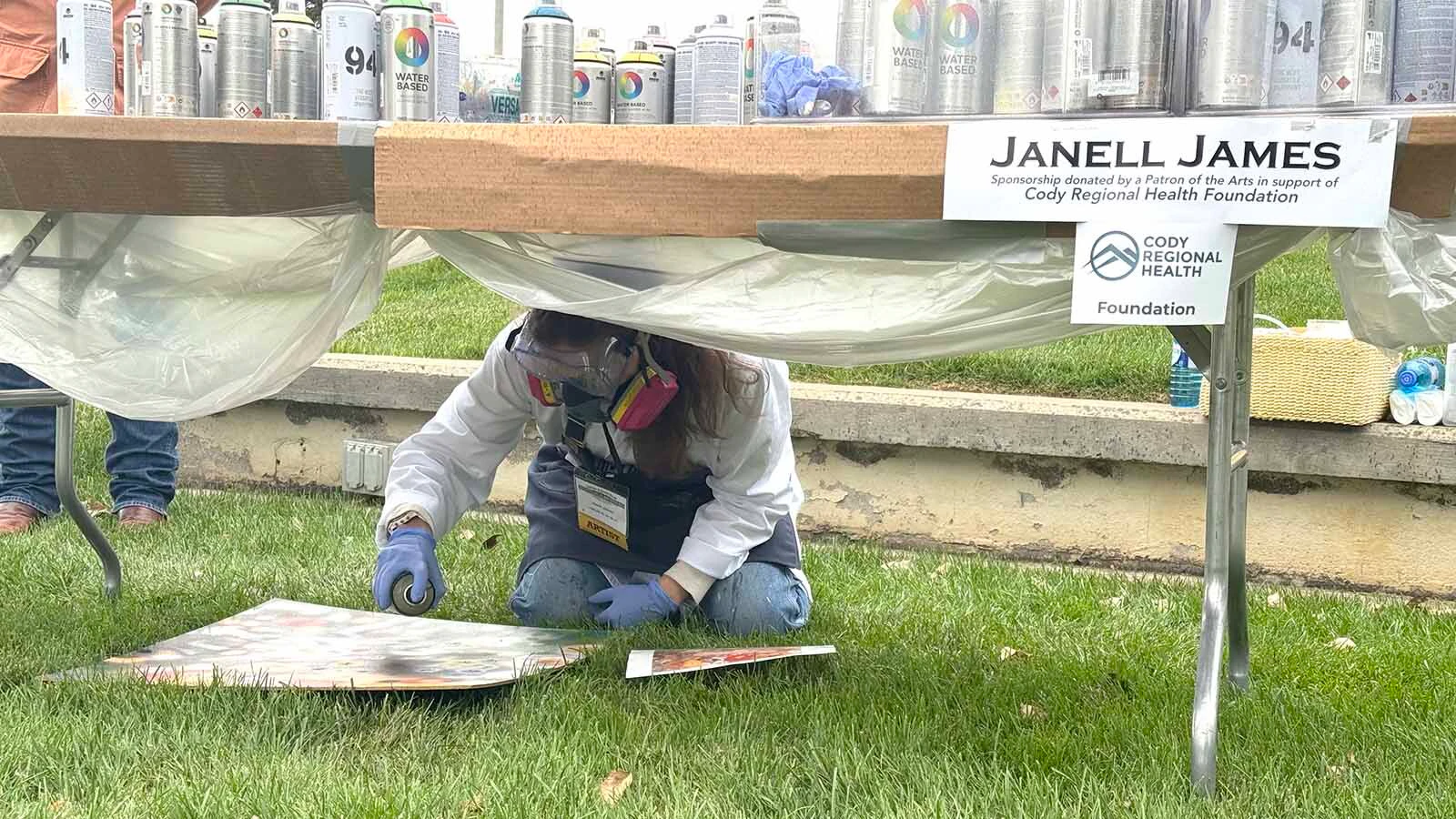Artist Janell James uses spray paint for her contribution to the 45th Buffalo Bill Art Show and Sale's Quick Draw on Saturday. When rain sent most other artists inside, James kept her mask on and continued working under the table to finish her piece. 