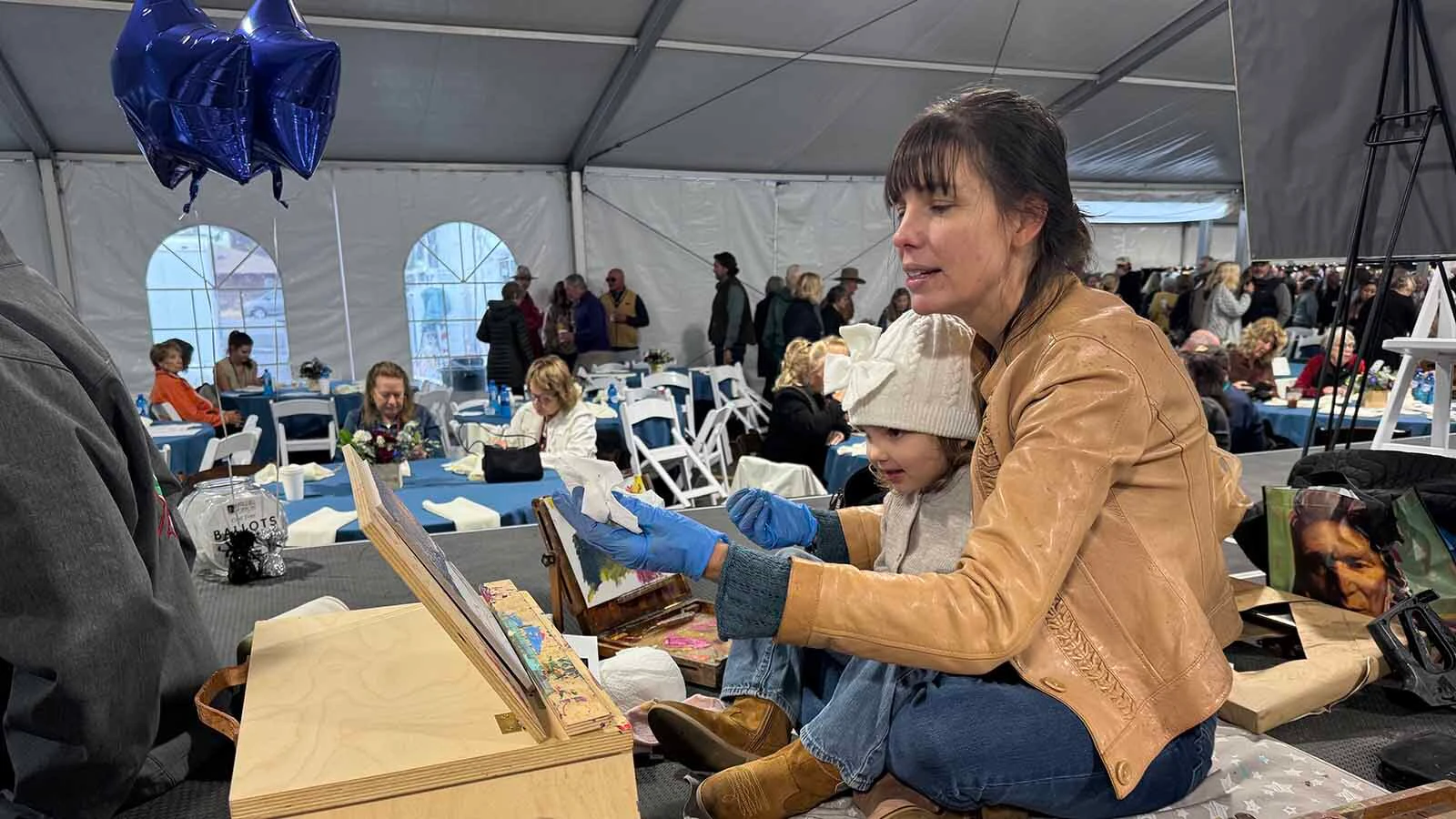 Artist Jessica Garrett-Lawrence works on an oil painting, with her daughter on her lap, during the 45th Buffalo Bill Art Show and Sale's Quick Draw.