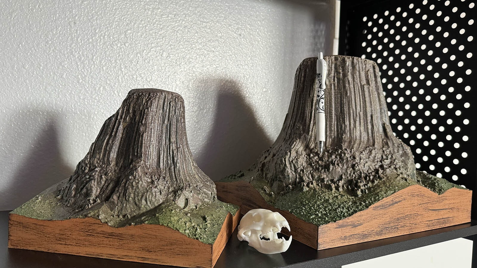Two 3D printed models of Devils Tower, with a pen for scale. The models themselves are solid plastic with hollow interiors and took between 20 and 40 hours to print.