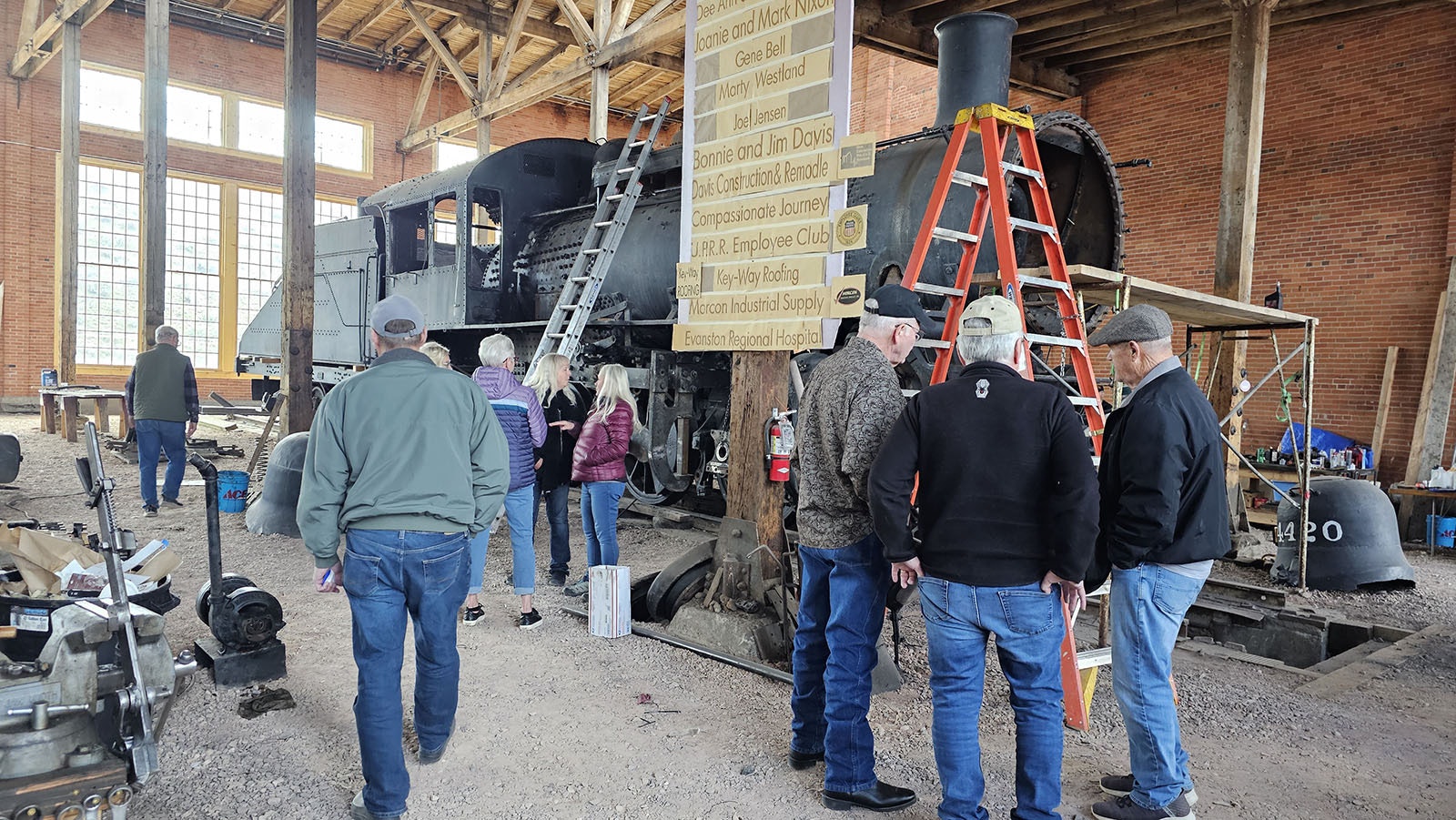 A group of people gather to look at 4420, a 110-year-old switch steam engine that's being restored in Evanston at the Roundhouse and Railyard.