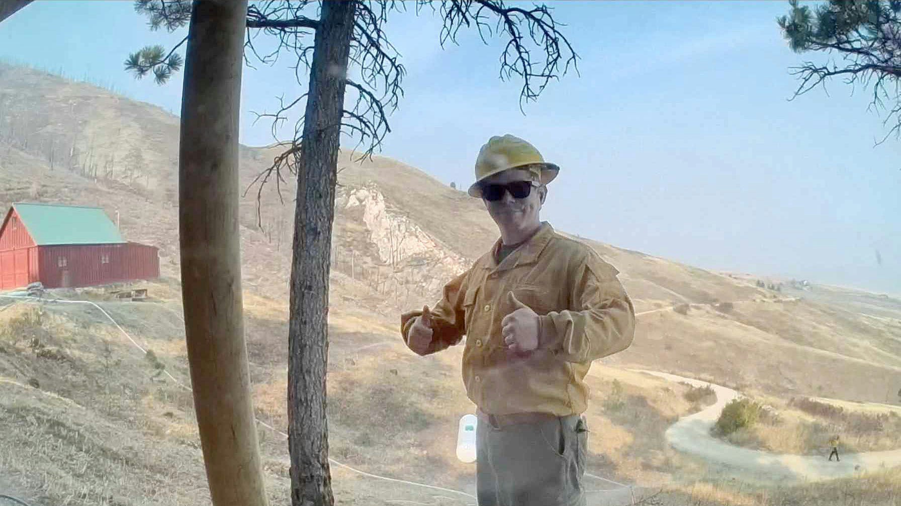 A firefighter gives a homeowner a big thumbs up in their home web camera in the Red Grade Road area.