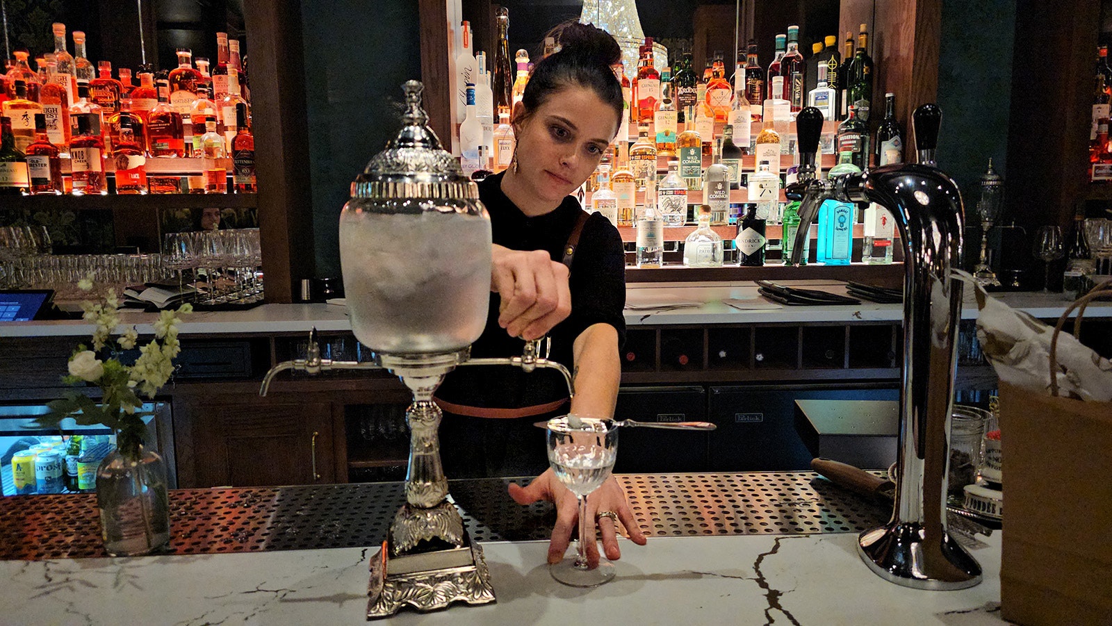 The bartender at Le Reve Restaurant and Raw Bar adjusts the flow of water from an ornate fountain, part of the ritual involved in serving a glass of absinthe.