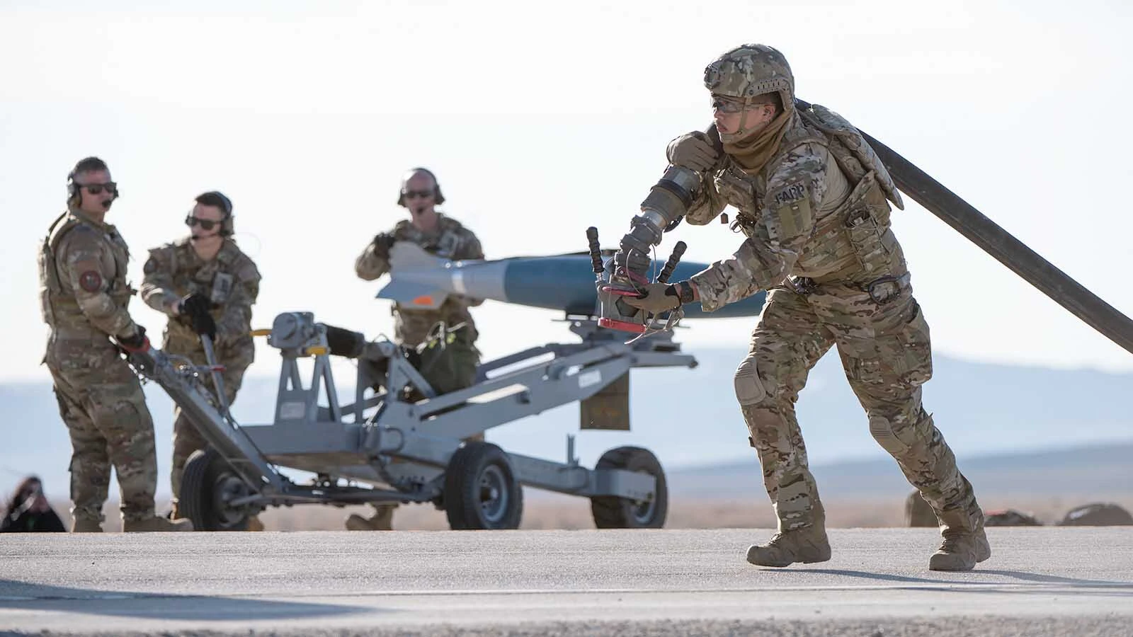 An Airman with the 1st Special Operations Wing Forward Arming and Refueling Point (FARP) team lines up a fuel hose to refuel an A-10 Thunderbolt II during Exercise Chariot, near Rawlings, Wyoming, April 30, 2023, while an Integrated Combat Turnaround team stands behind him waiting to upload weapons onto the aircraft.