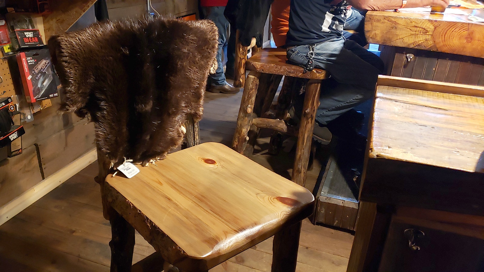 Furs that are for sale adorn each of the rustic chairs in the bar.