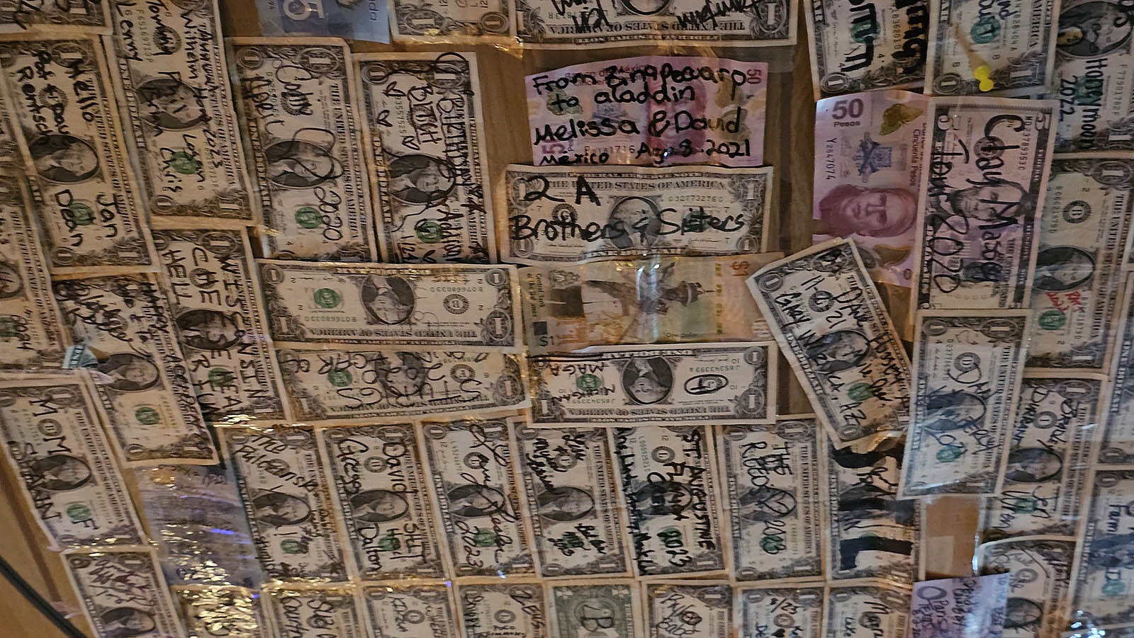 Visitors like to leave dollar bills with messages on them. They're taped to the ceiling in the Aladdin General Store's bar.