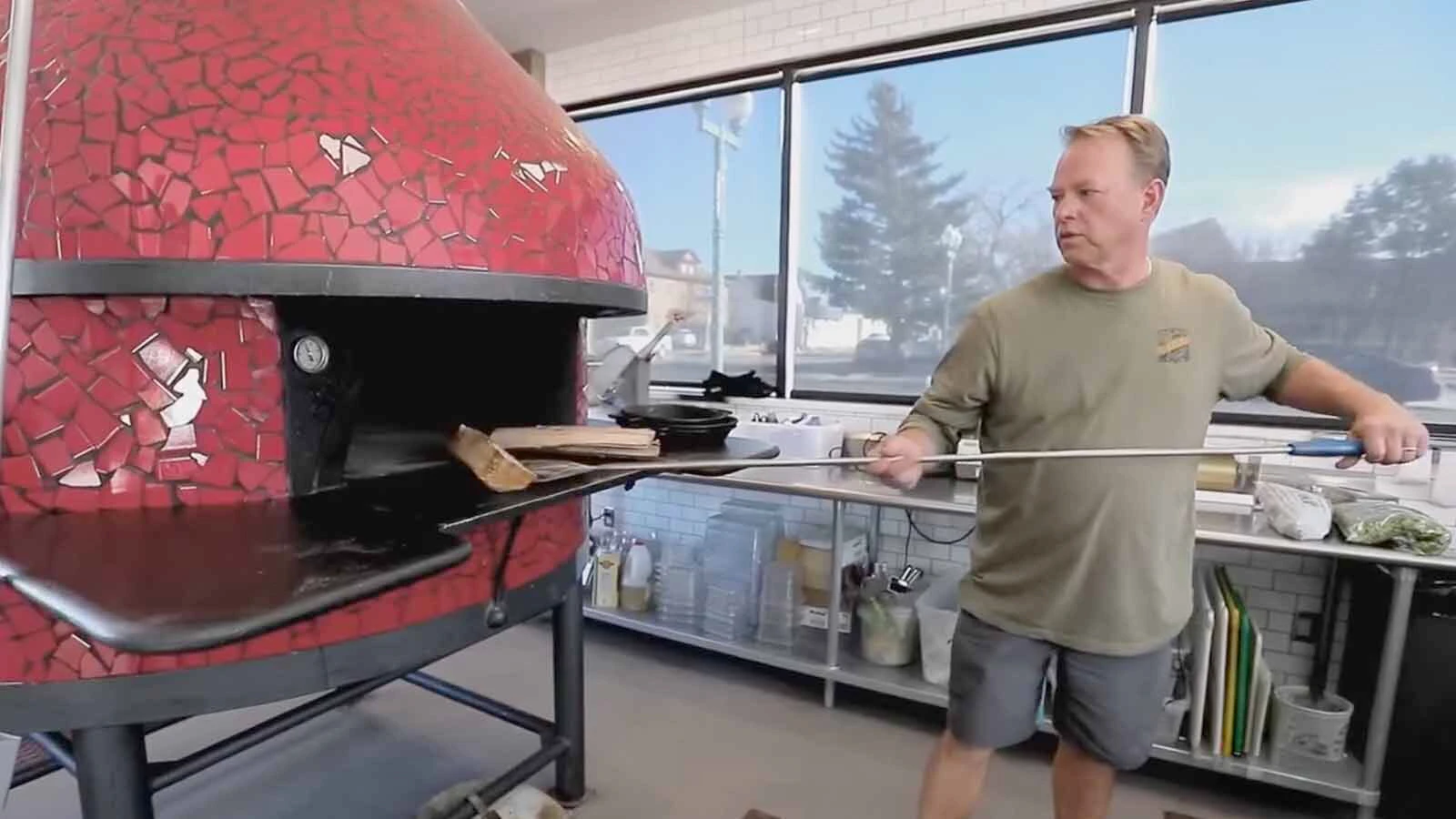 Alibi Wood Fire Pizzeria & Bakery co-owners Ethan Smith loads the wood-fired oven while on "Diners, Drive-Ins & Dives" in 2022.