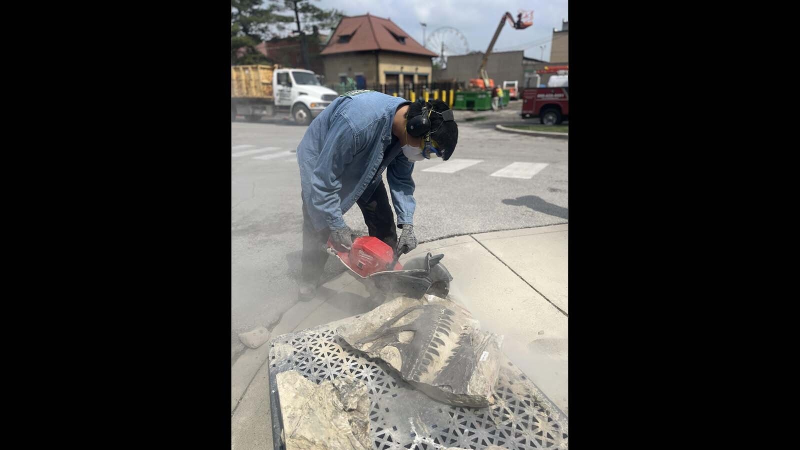 A rock saw is used to "slim down" the sandstone block containing the articulated skull of an Allosaurus at the Children's Museum of Indianapolis. Laura Rooney, curator of paleontology at the museum, arranged for the blocks to be CT-scanned for an inside look at the fossils inside, but they needed to lose some weight before they could fit inside the machine.