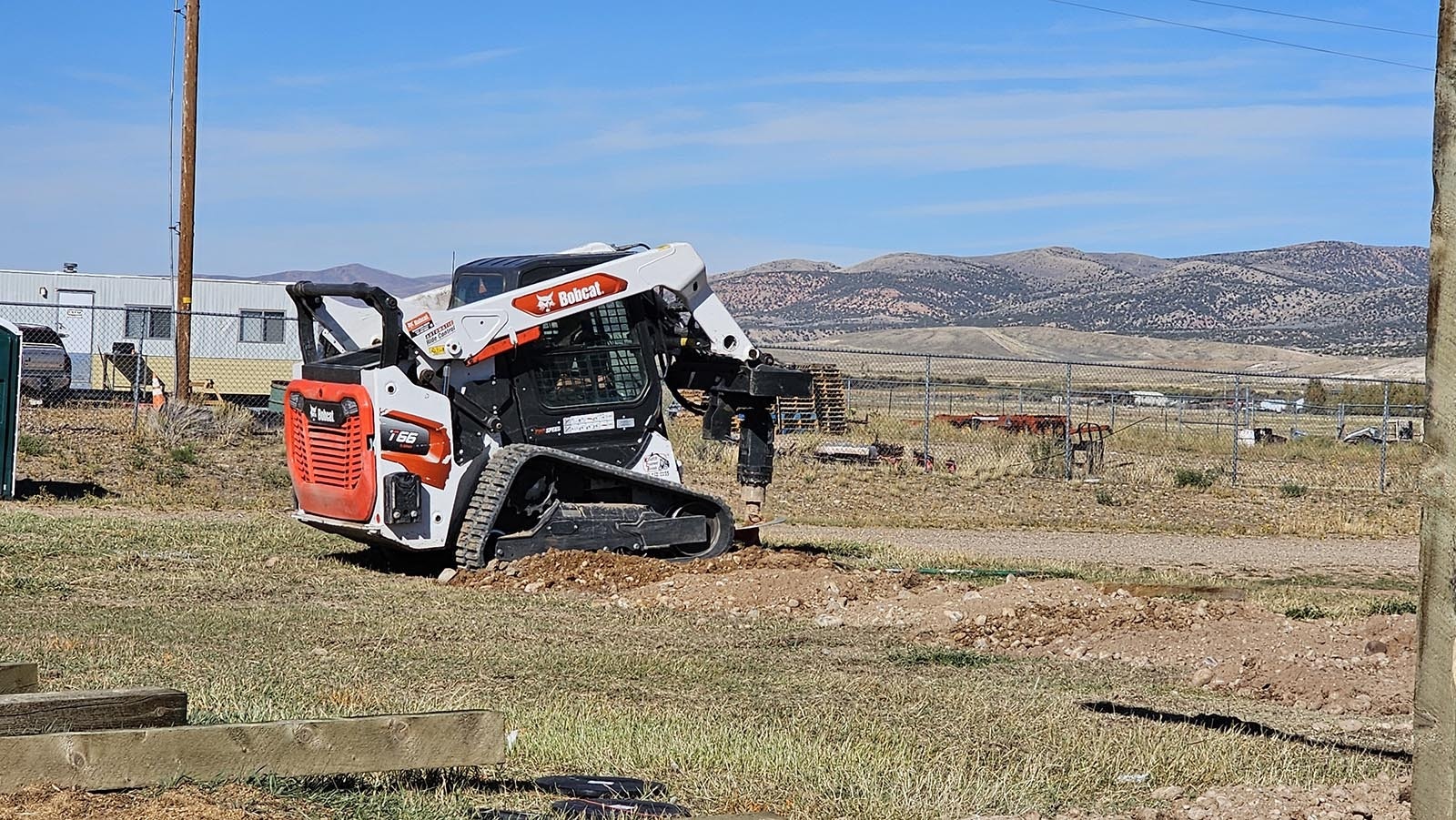 A bobcat with a rotary drill attached was used to drill postholes for a barn being raised by an Amish crew from Ohio.