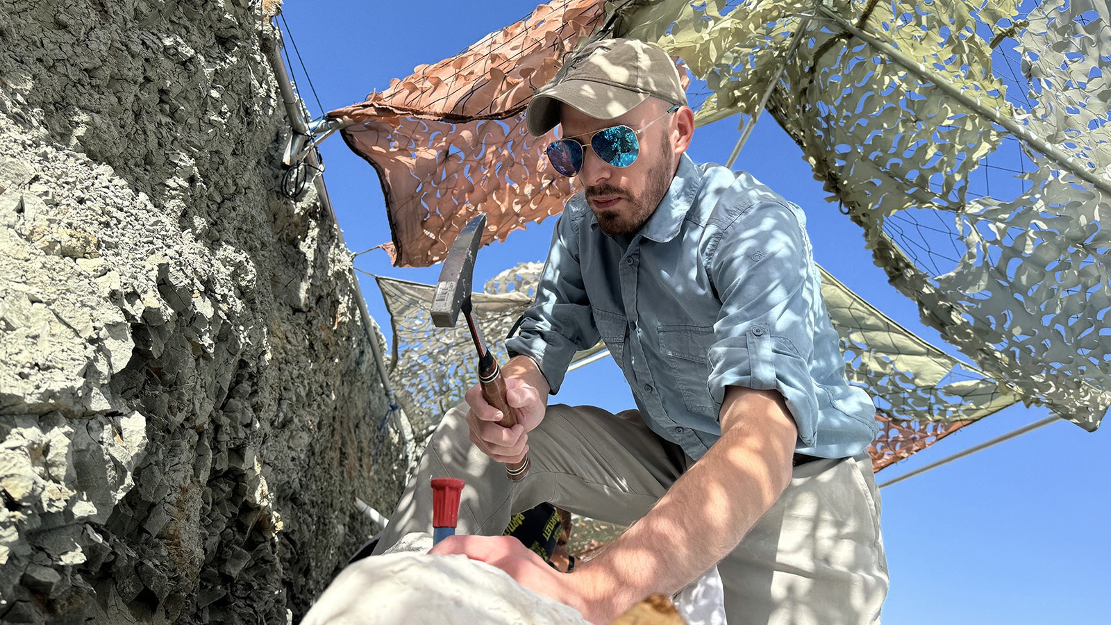 Andrew Rossi chiseling and isolating a jacket of dinosaur fossils at the Nail Quarry near Medicine Bow.