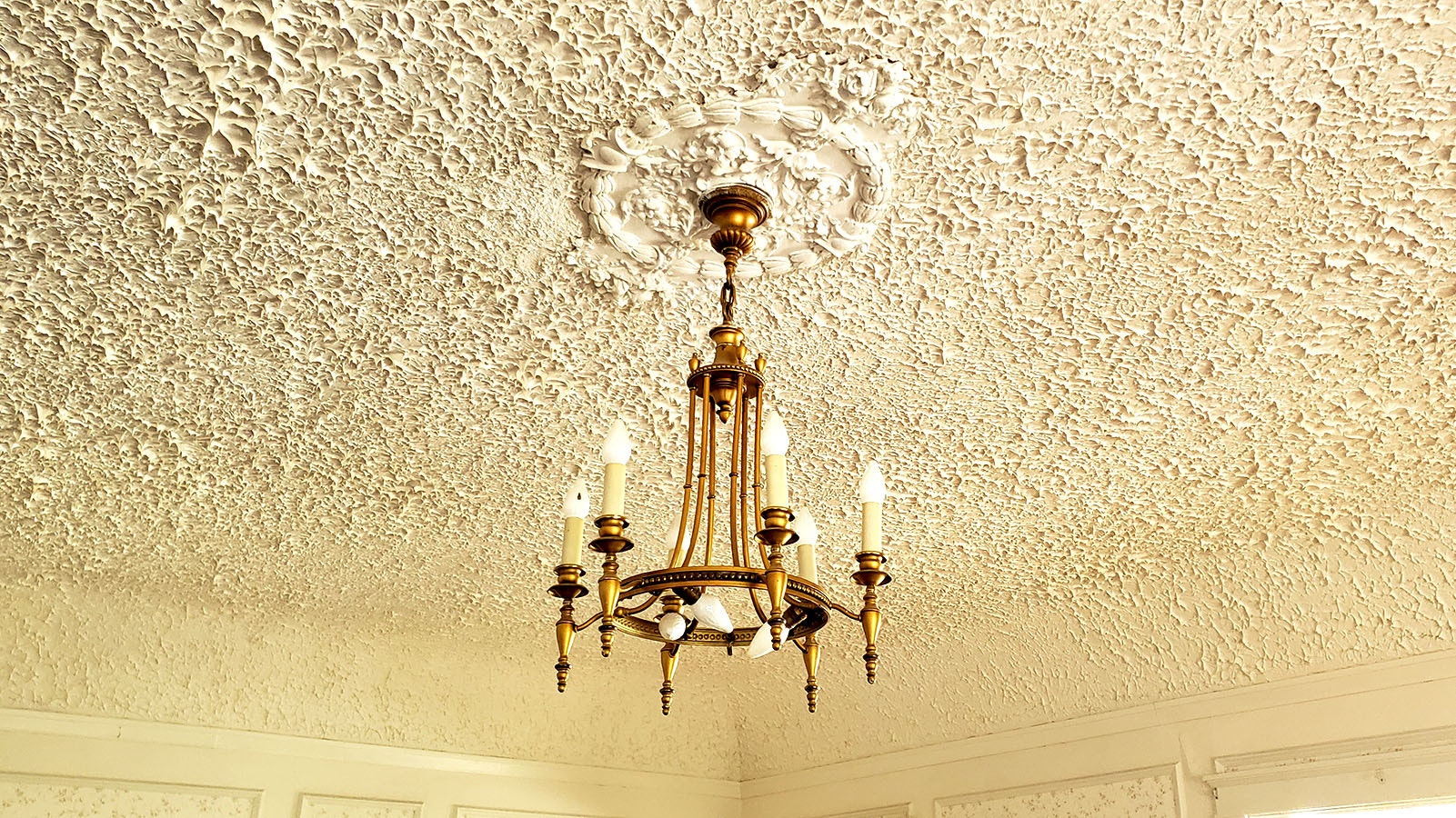 An elaborate ceiling with gold chandelier at the Arapaho Ranch mansion.