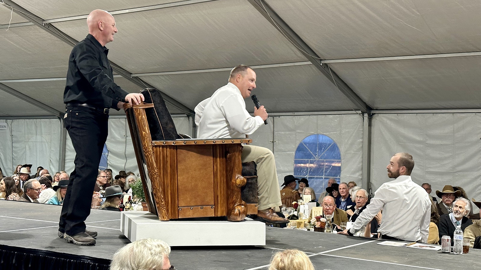 Auctioneer Troy Black takes a ride on a Molesworth-style club chair built by Ian Gallis of By Western Hands during the 42nd Buffalo Bill Art Show and Sale Live Auction. The chair sold for $10,000.