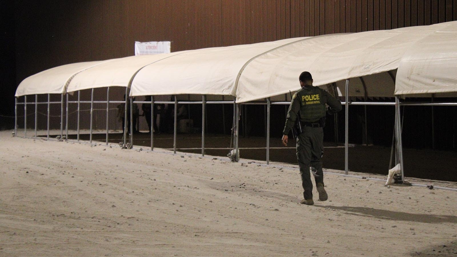 A border patrol agent approaches the recently crossed immigrants.