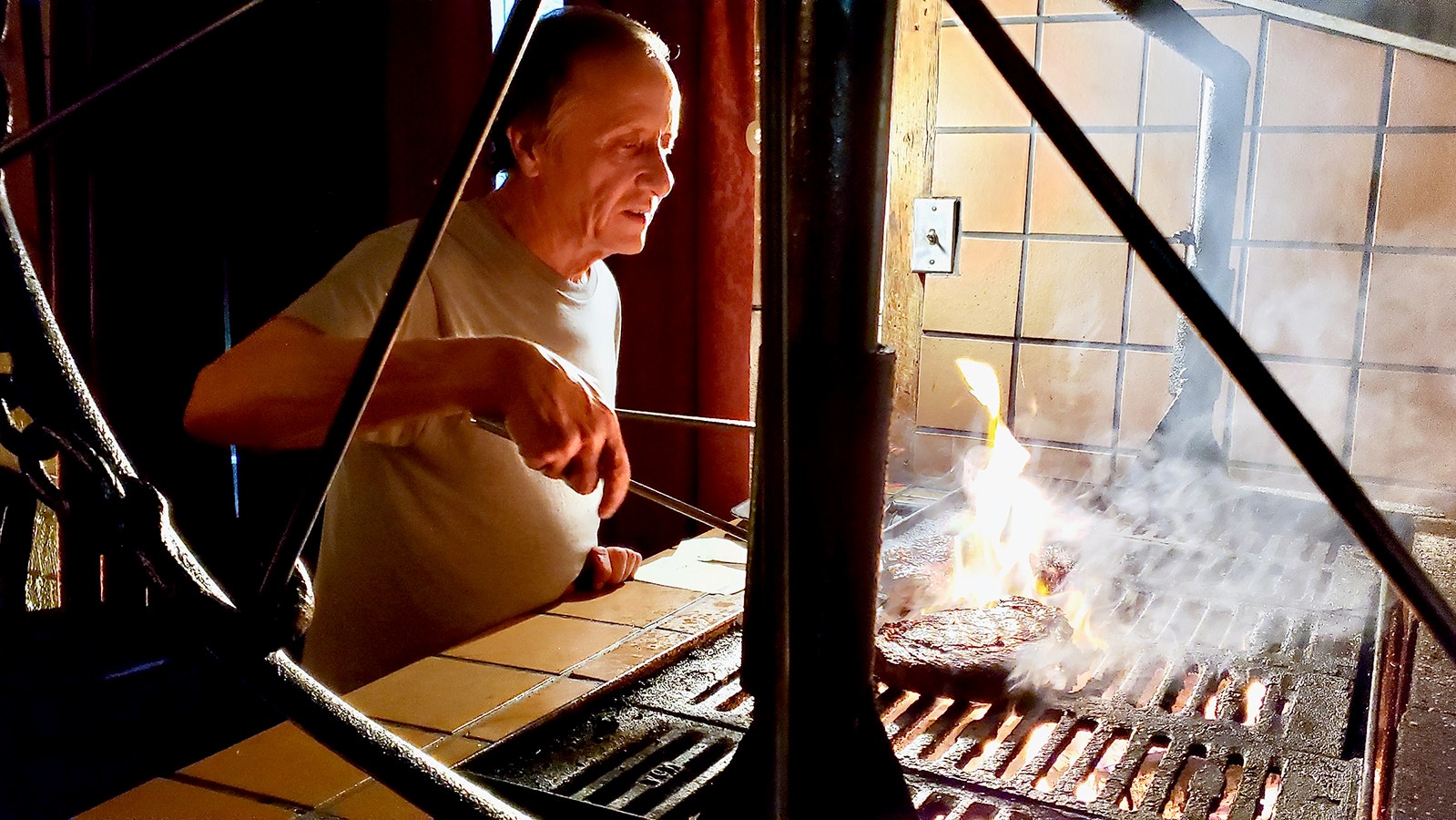 Ron Abernathy flips a steak over an aspen wood fire.