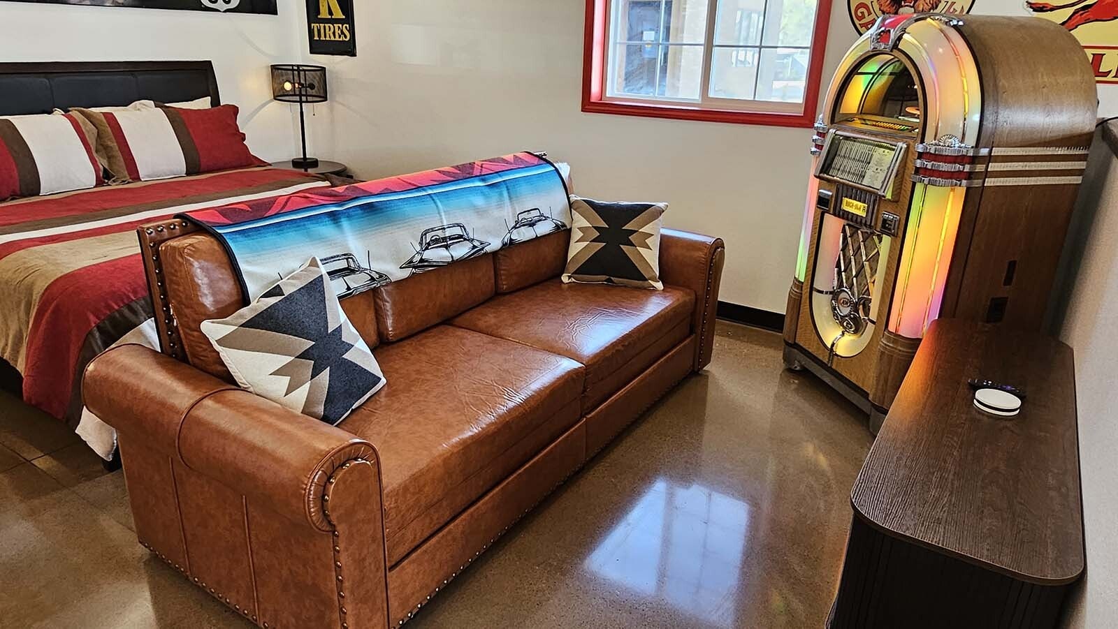 A comfy couch is all set up for listening to tunes streamed to the old-fashioned juke box, which has been retrofitted with Bluetooth technology.  The scene is part of a vintage automobile-themed Airbnb recently completed by Jeff Wandler, who owns Frontier Auto Museum in Gillette.