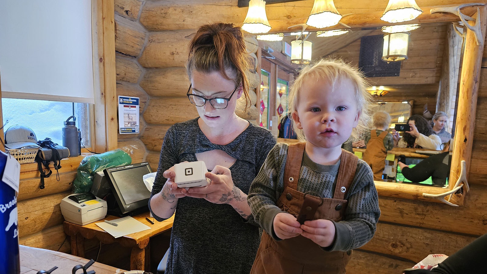 Aspen Conner pauses to look up for a moment from looking at the souvenirs a guest is buying from Brooks Lake Lodge while her mother, Victoria, processes a transaction.