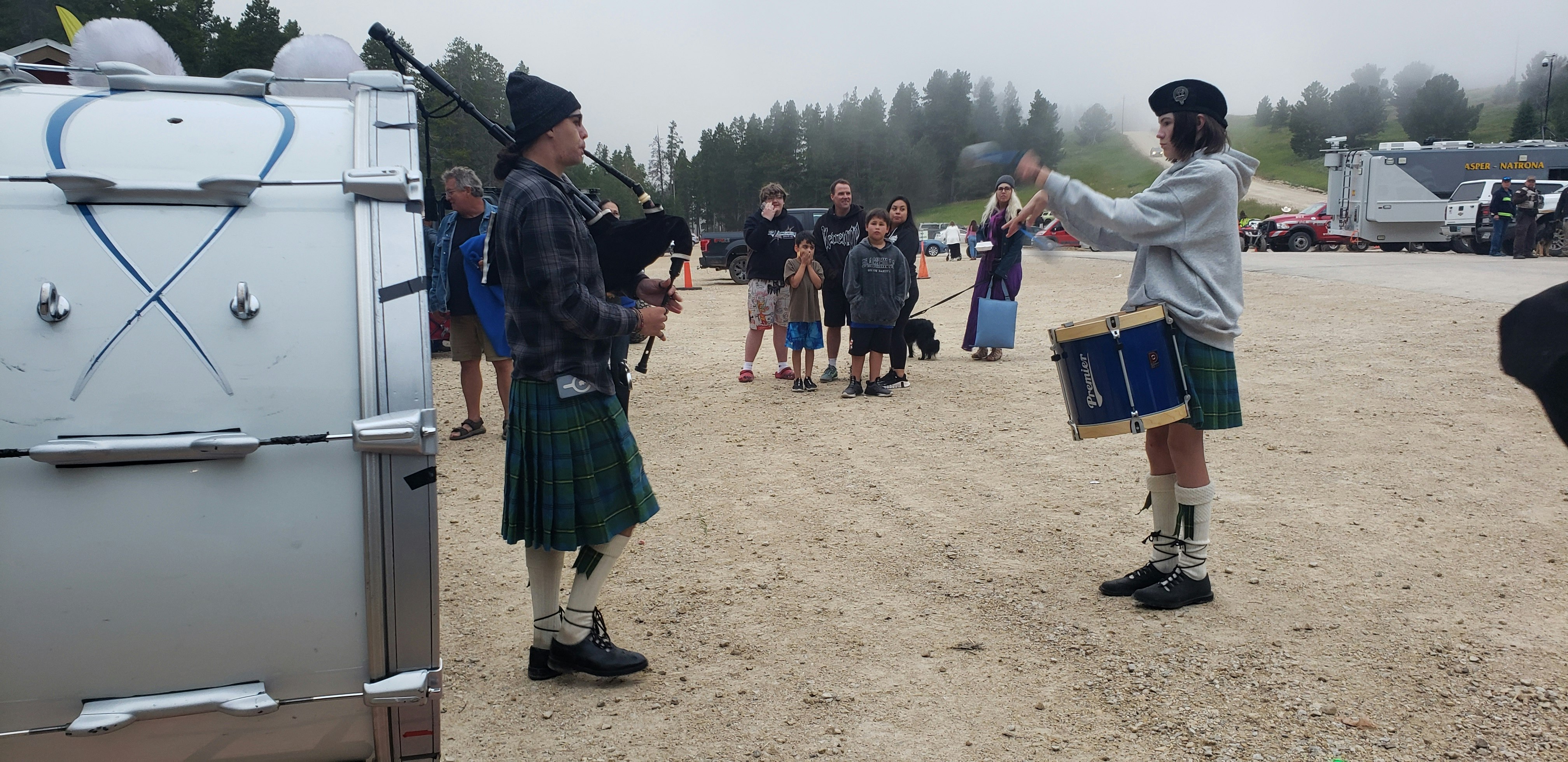 A drummer twirls his sticks while a bagpiper plays.