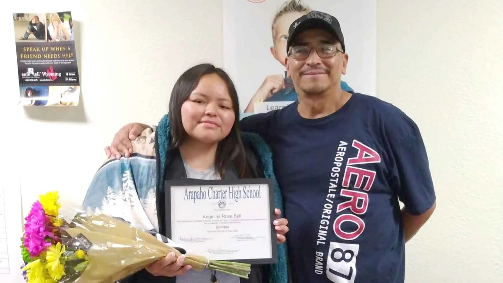  Angelina Bell holds her Arapaho Charter High School diploma while standing with her father, Byron Bell.