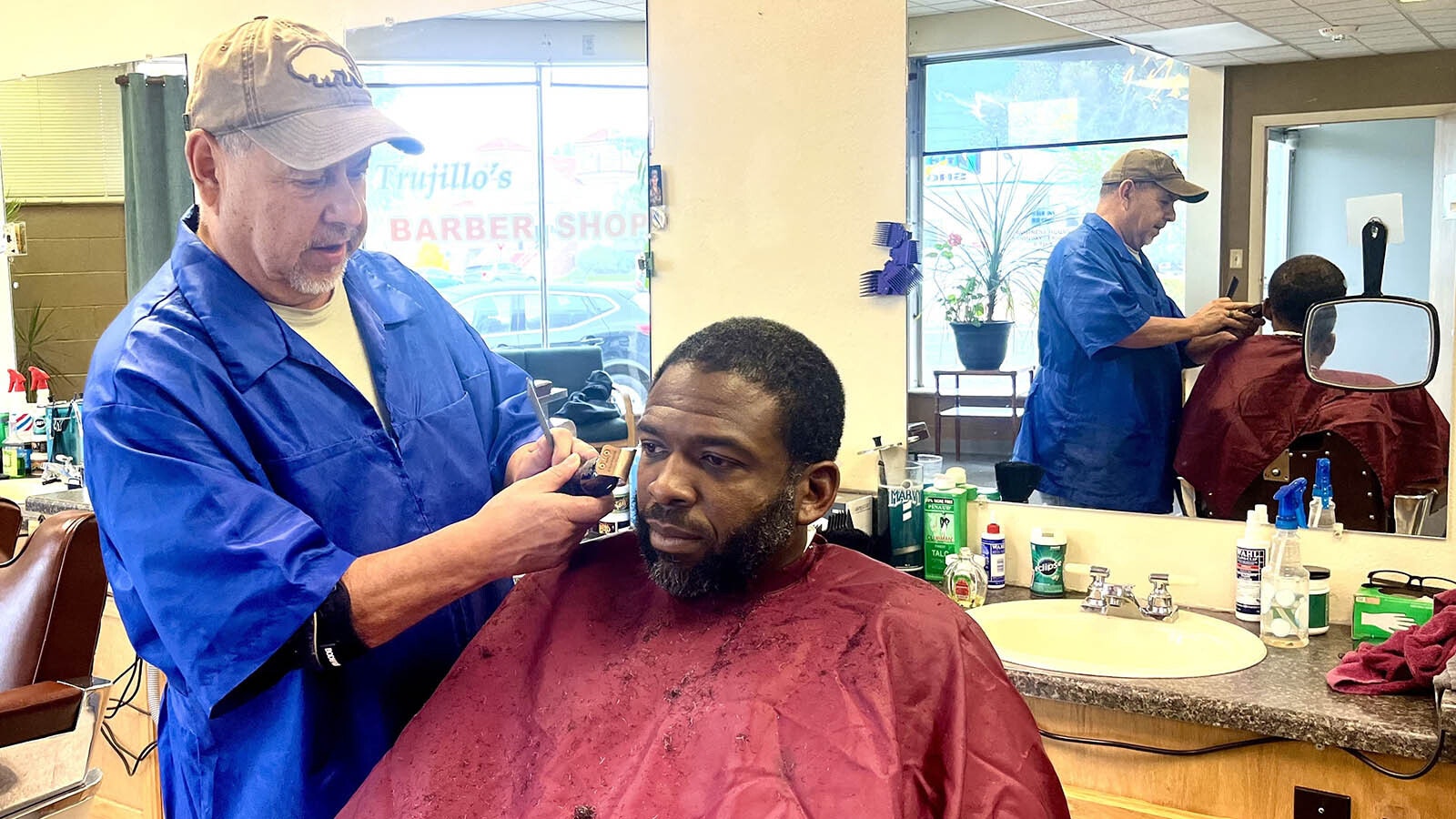 Glen Chavez, left, of Trujillo’s Barber Shop cuts Reshaun Cann’s hair.