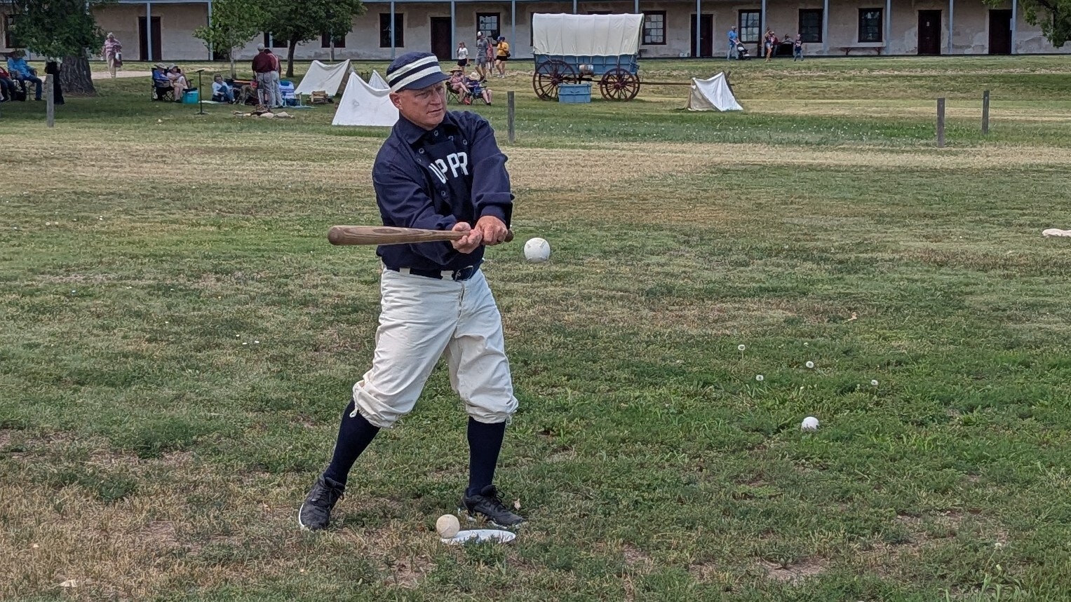 A batter strikes a ball during a demonstration of the National Pastime under the rules of the 1860s during the Fort Laramie National Historic Site Independence Day celebration.