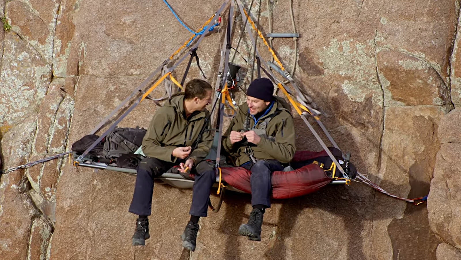 Bear Grylls and actor Bradley Cooper take a meal break hanging from a sheer cliff wall in Wyoming.