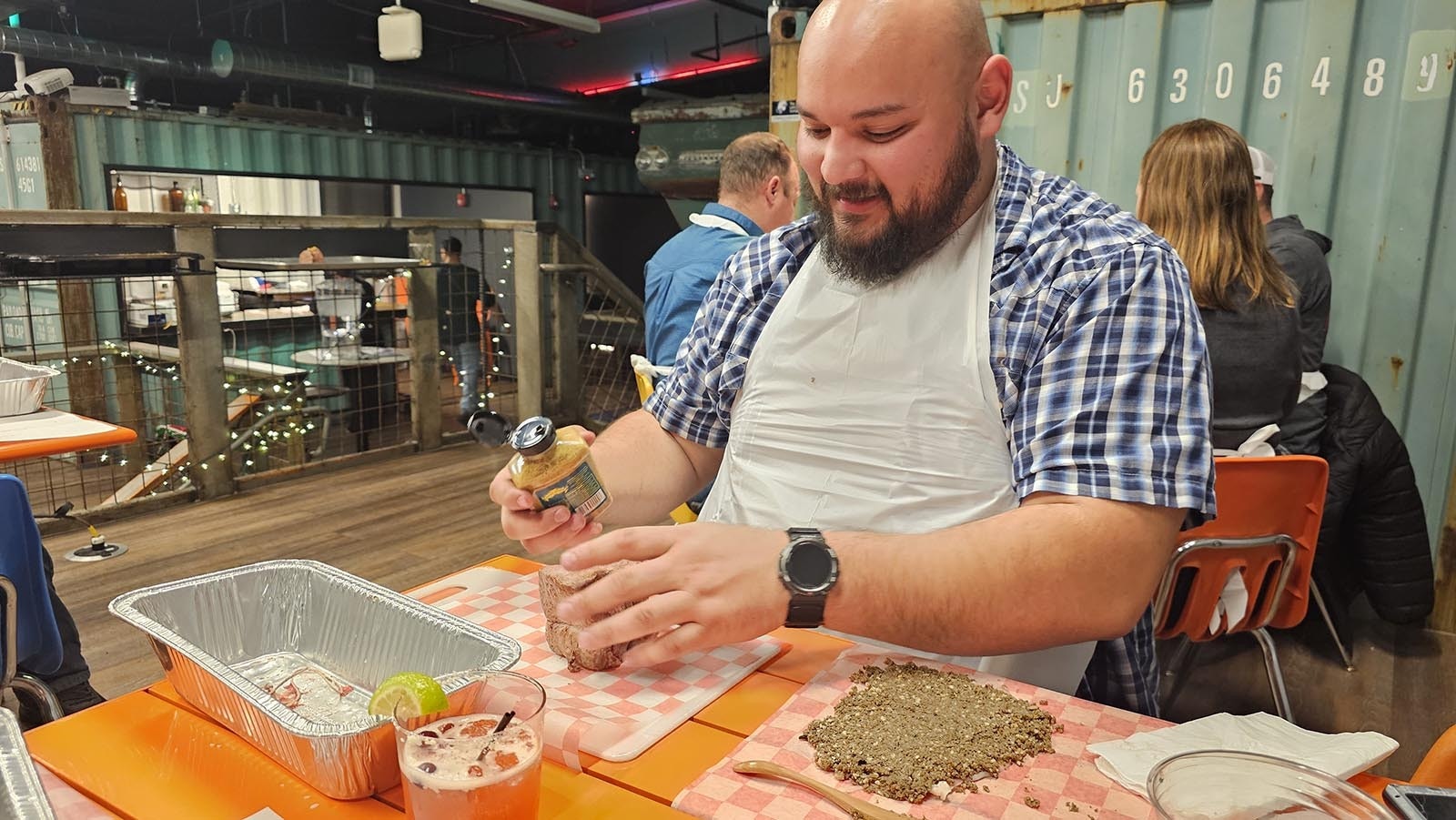 Eli Vurgess puts mustard on a tenderloin prior to wrapping it with prosciutto and mushroom duxelles during a beef Wellington class at Railspur.