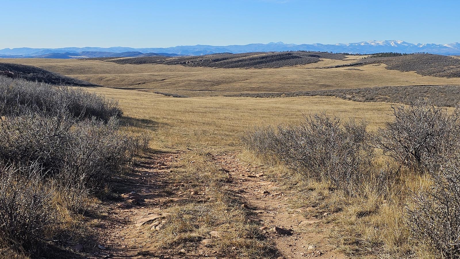 The Rocky Mountains on the horizon help frame the Belvoir Ranch recreation area as users start to descend into its bowl, which was created by an ancient geological lift.