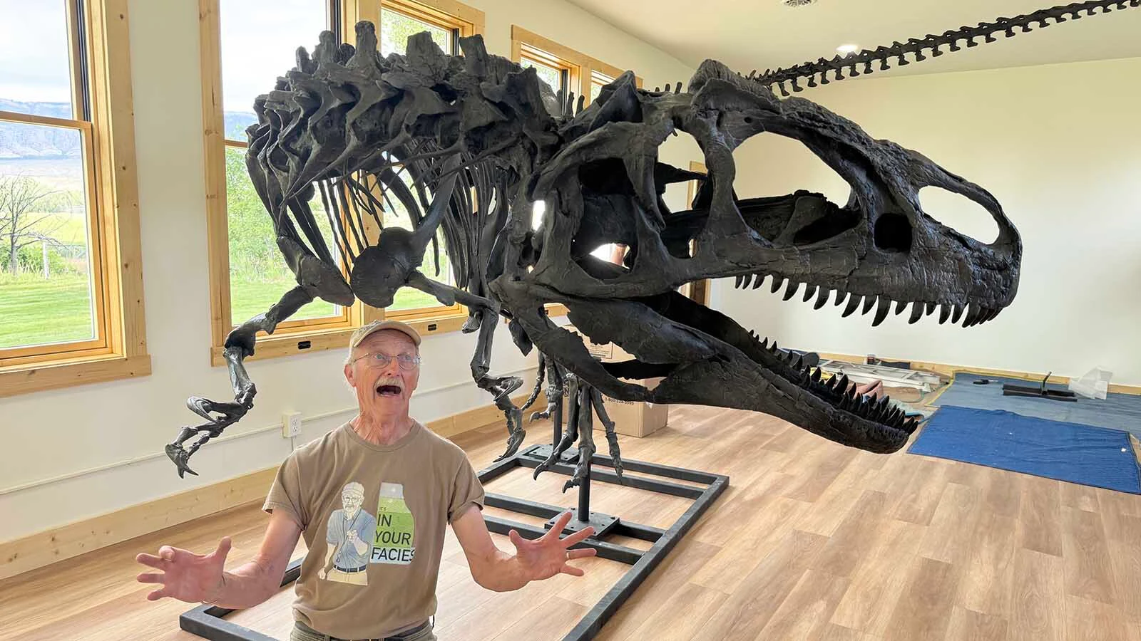 Erik Kvale, president of the Wild West Dino Den, in the menacing arms of "Big Al" in the Historic Red Shell Schoolhouse. Big Al,  found near Shell in 1991, is one of the most famous dinosaurs ever found because of its injury-addled skeleton. 