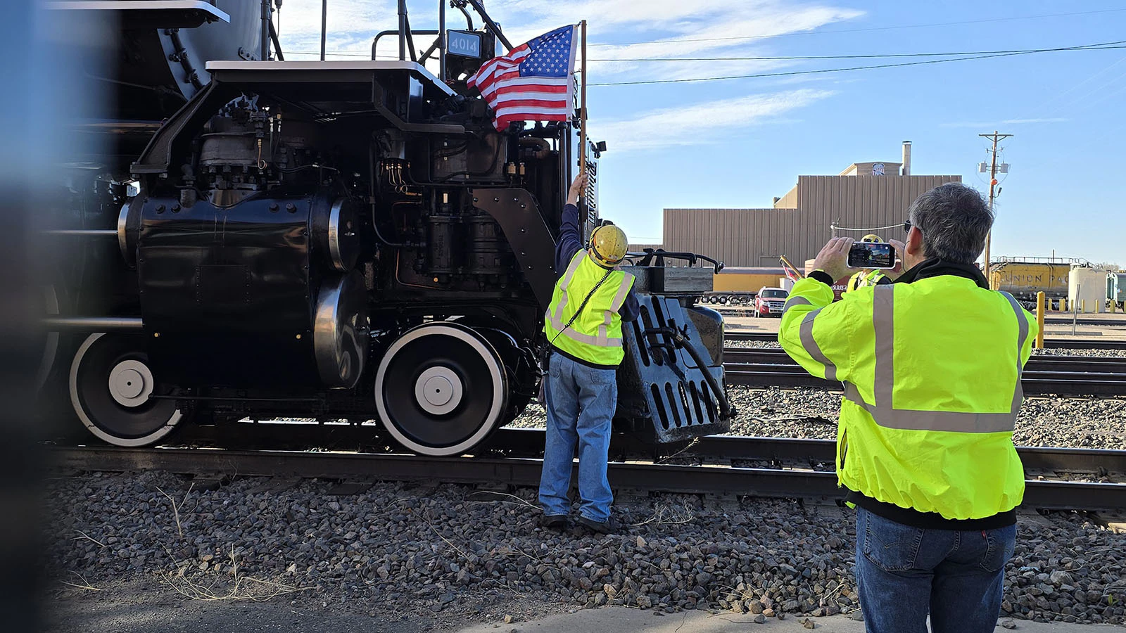 A Union Pacific worker films a fellow worker affixing an American flag to Big Boy ahead of its departure from Cheyenne.