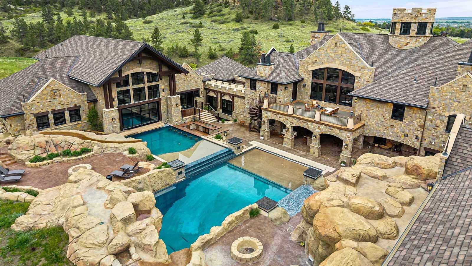 The property at 5650 Canyonwoods Drive in Billings, Montana, is described as a 30,843-square-foot stone chateau with 10 bedrooms and 19 bathrooms, situated on 98 acres. The listing mentions it's priced at $26.9 million and includes amenities like three pools, a 14-car garage, elevators, indoor shooting range, bowling alley, an outdoor 3-hole golf course and an indoor golf simulator, plus a wine cellar, workout gym and theater.