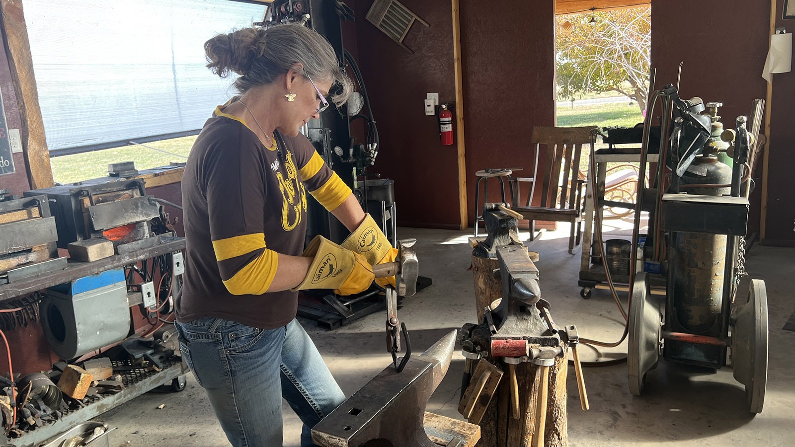 Audra Draper swings a hammer to shape a piece of hot metal in her shop near Riverton.