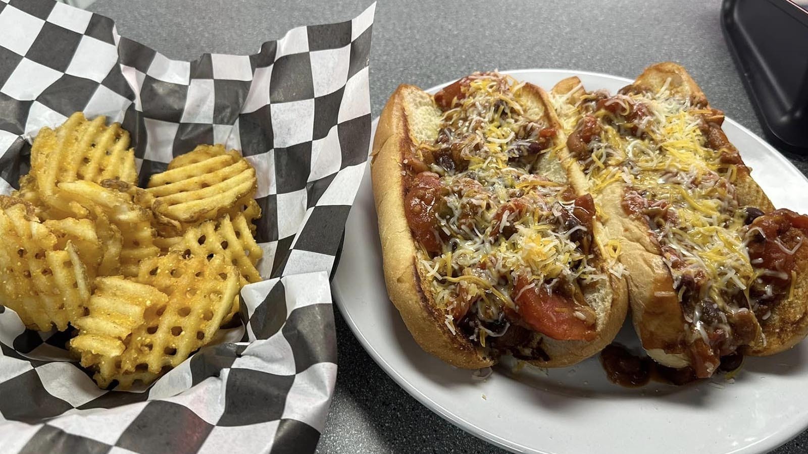 A pair of chili dogs and waffle fries.