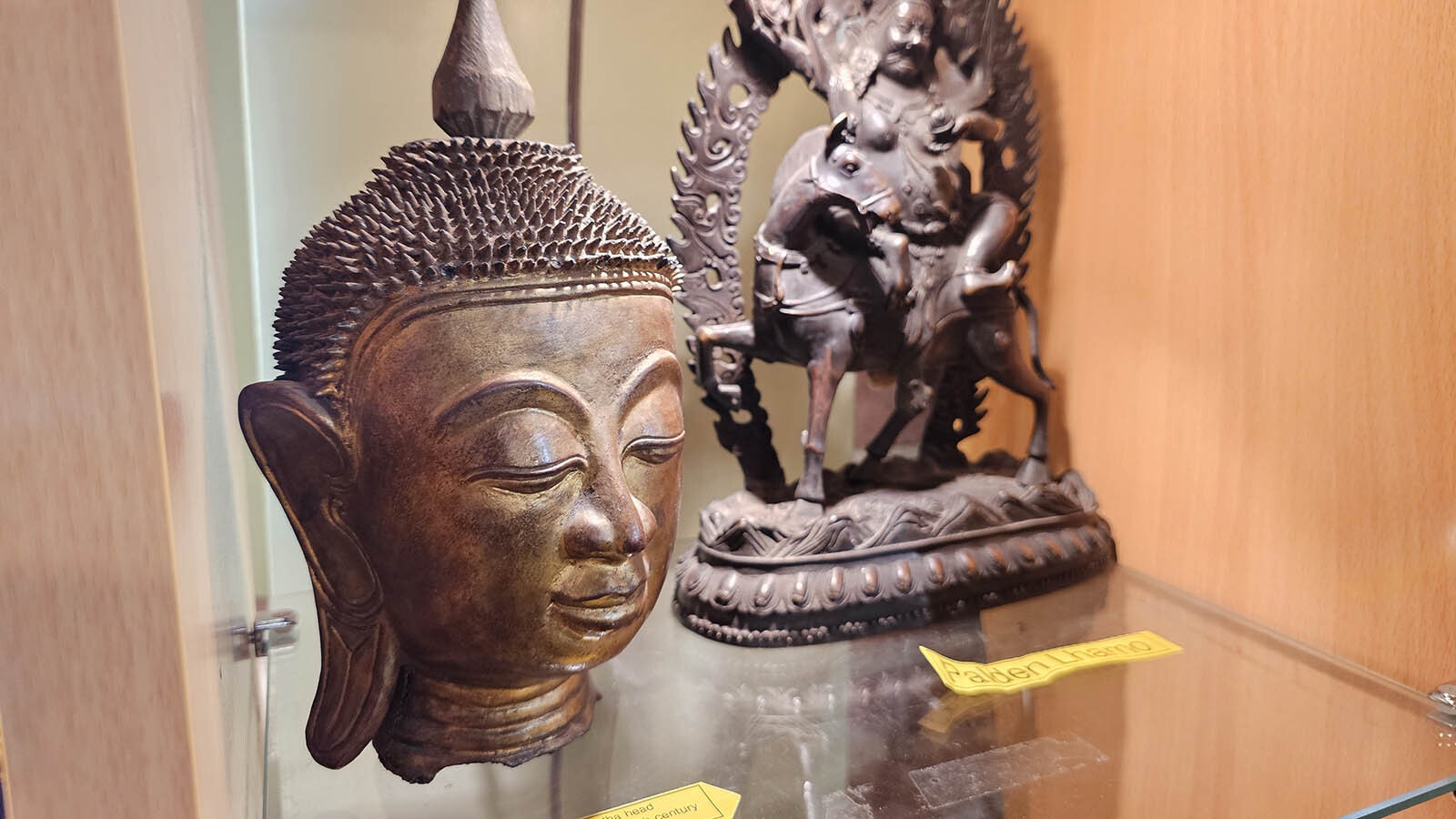 A wooden Buddha head from the late 19th or early 20th century from Burma (Myanmar), left, and a Palden Lhamo, back.