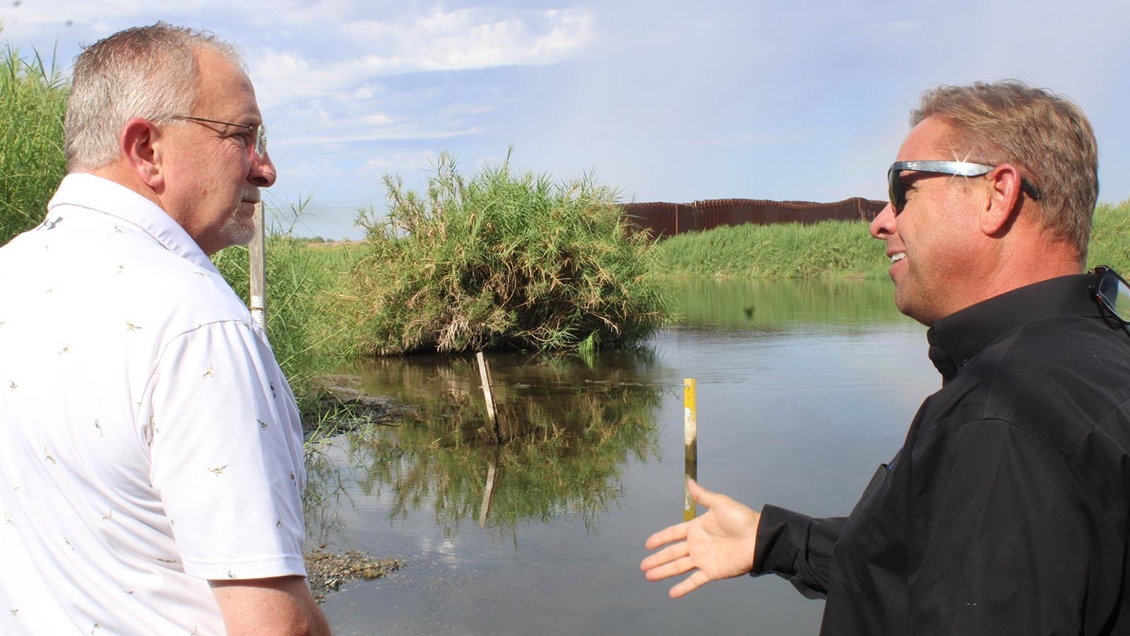 Yuma County Supervisor Jonathan Lines, right, explains to state Rep. Jon Conrad, R-Mountain View, how people can more easily cross from Mexico on the left side of the wall in the background, over to California on the right, rather than travel across the Colorado River to Arizona where they stand.