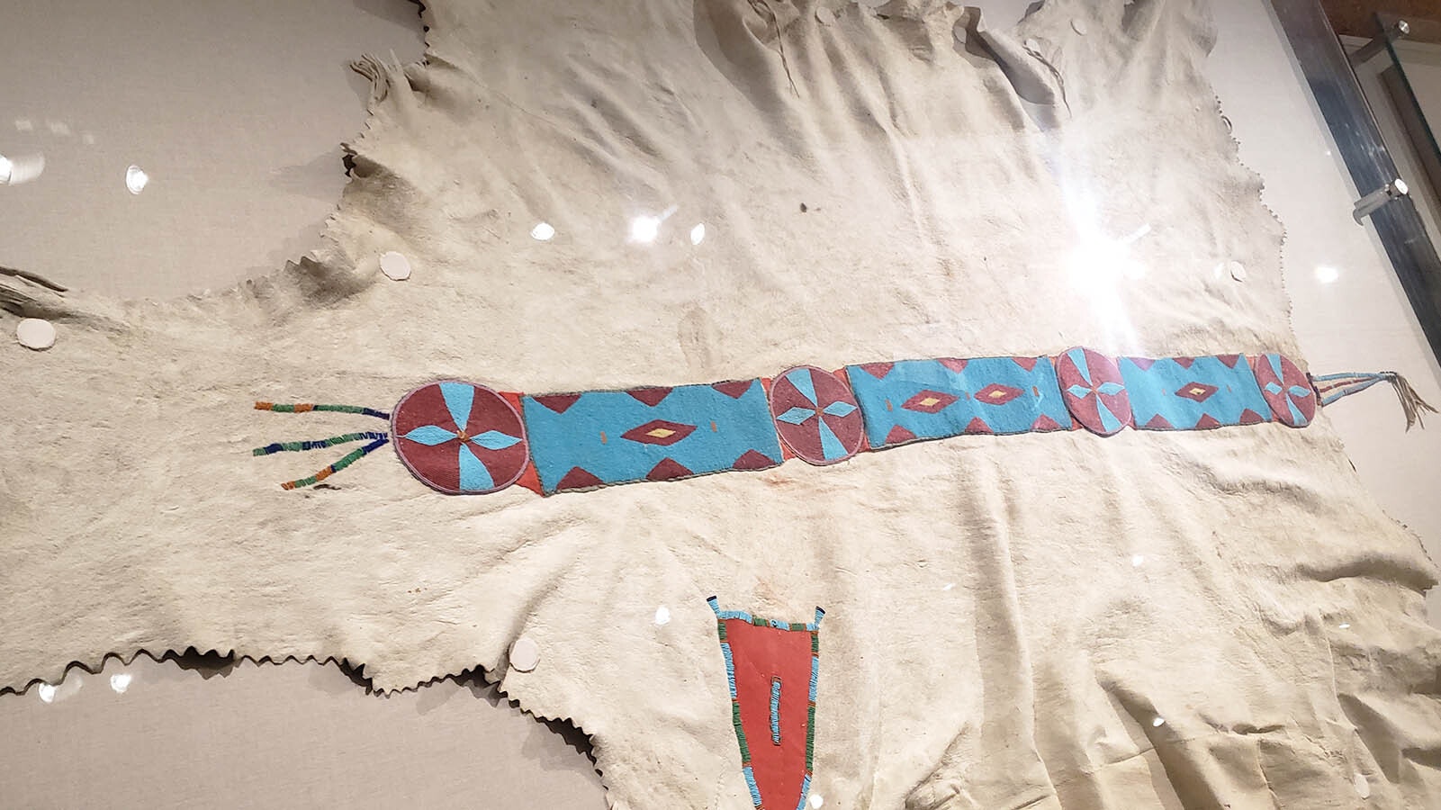 Cheyenne women often used a split-robe, where two pieces of hide were sewn together through the middle of the hide. The colorful strip depicts a specific event regarding the tribe’s military societies.