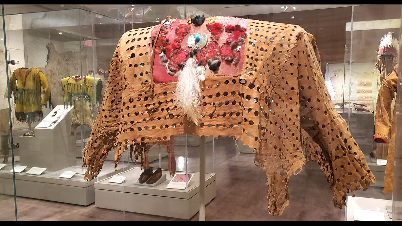 A grizzly bear shirt made of deer hide, bird breast feathers, shell and glass beads, mallard and woodpecker scalp. Blackfeet warriors wearing these had power to heal wounds suffered in battle and were protected in battle.