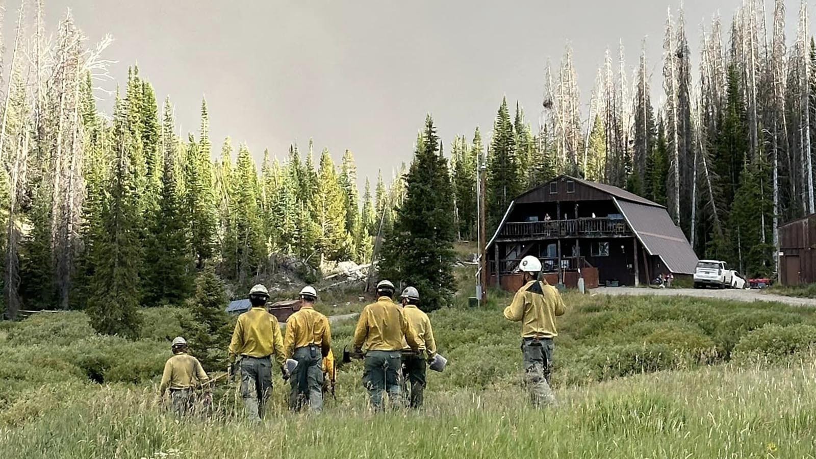 Firefighters work to protect the 102-year-old historic Brooks Lake Lodge from the Fish Creek Fire burning in northwest Wyoming.