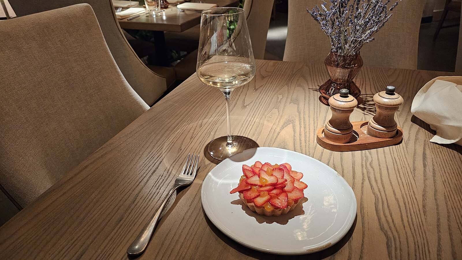 A strawberry tart, arranged to look like a rose, with an orange sauce, piled on top of a vanilla custard in a crispy crunchy shell.