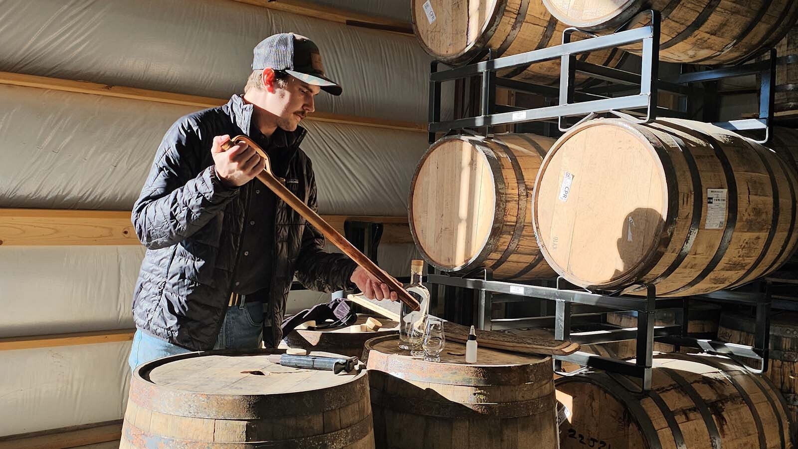 Brush Creek Ranch Lead Distiller Ethan Whitman demonstrates how to "thieve" from a whiskey barrel.