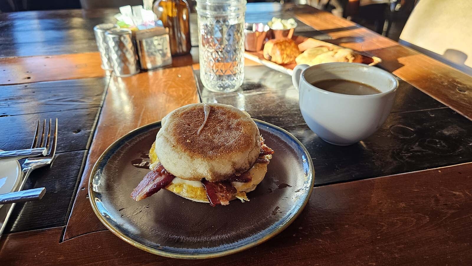 A breakfast sandwich on toasted English muffin with an almond milk latte.
