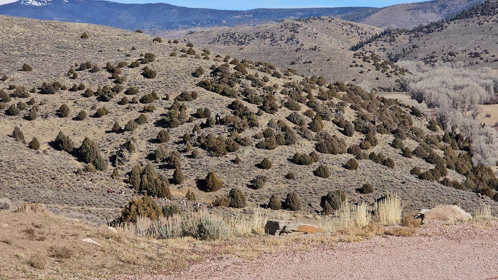 A group of horseback riders appear tiny in comparison to the mountains and hills surrounding Brush Creek Ranch.