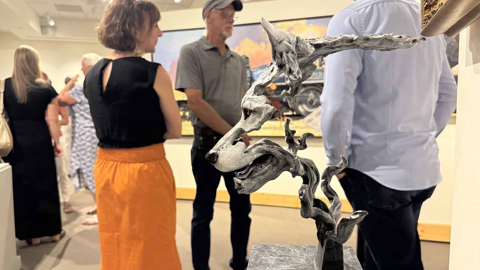 People chat next to "Intero," a bronze sculpture by Amanda Markel, at the opening of the 44th Buffalo Bill Art Show and Sale.
