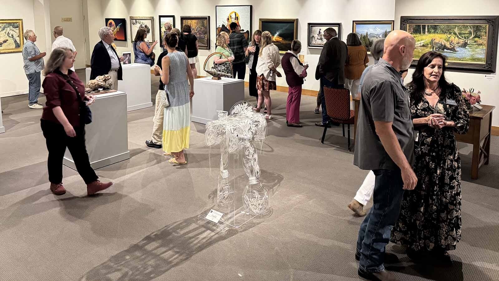 People perusing the gallery of art selected for the 44th Buffalo Bill Art Show and Sale. The unique piece at the center is "Crystal Road," made of hand-etched and hand-formed acrylic by Maeve Eichelberger.