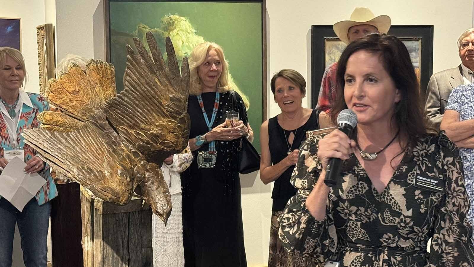 Rebecca West, executive director of the Buffalo Bill Center of the West, addresses the gallery attendees next to "Earth, Wind and Fire," a bronze sculpture by Paul Rhymer, at the opening of the 44th Buffalo Bill Art Show and Sale.