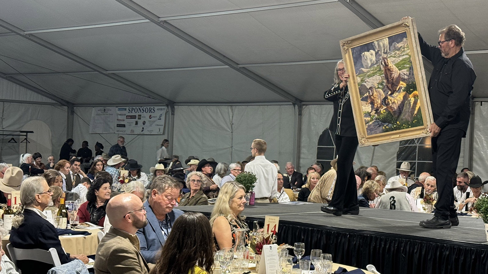 Patrons at the 43rd Buffalo Bill Art Show and Sale's live auction considering bidding on "The Three Marmoteers" by Dustin Van Wechel. The painting sold for $11,000.