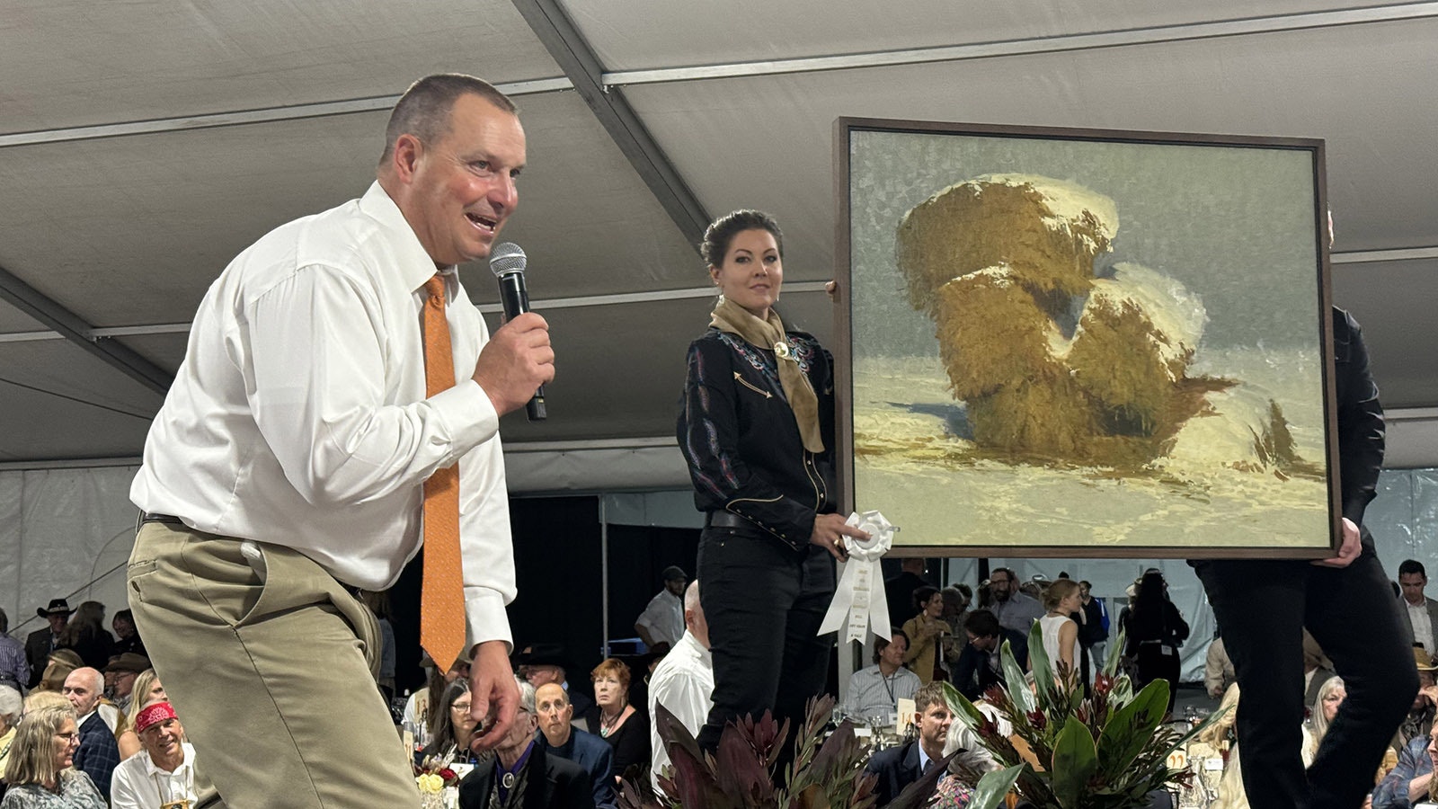 Auctioneer Troy Black goads a patron into taking another look (and making another bid) at "The Things We've Handed Down" by David Dibble. The painting sold for $18,000. Angela M. "Gigi" Hawks holding painting.