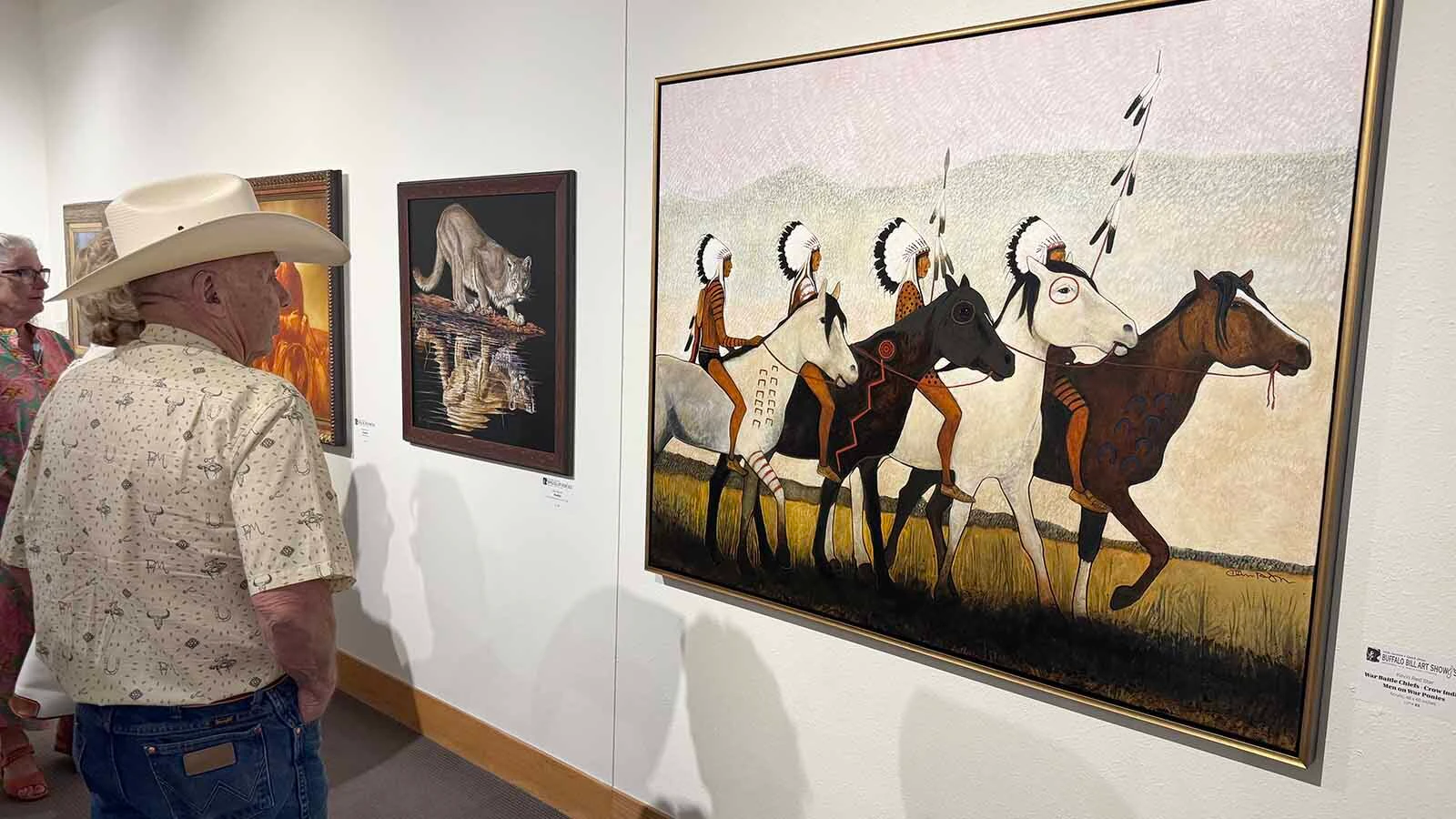 Patrons admire "War Battle Chiefs - Crow Indian Men on War Ponies," an acrylic painting by Kevin Red Star, at the Buffalo Bill Center of the West in Cody during the opening of the 45th Buffalo Bill Art Show and Sale.