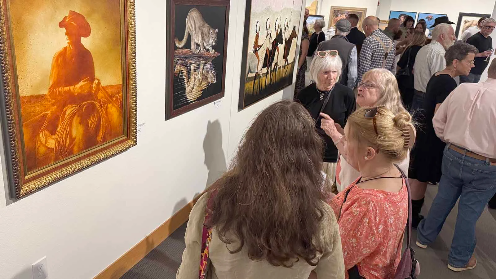 Patrons admire some of the 107 pieces of modern Western art that will be displayed and auctioned off during the opening of the 45th Buffalo Bill Art Show and Sale.